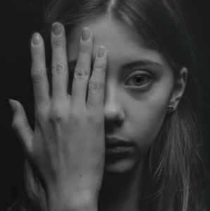 grayscale photo of woman covering her face by her hand
